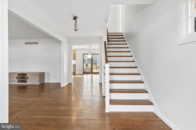 staircase with hardwood / wood-style flooring and crown molding