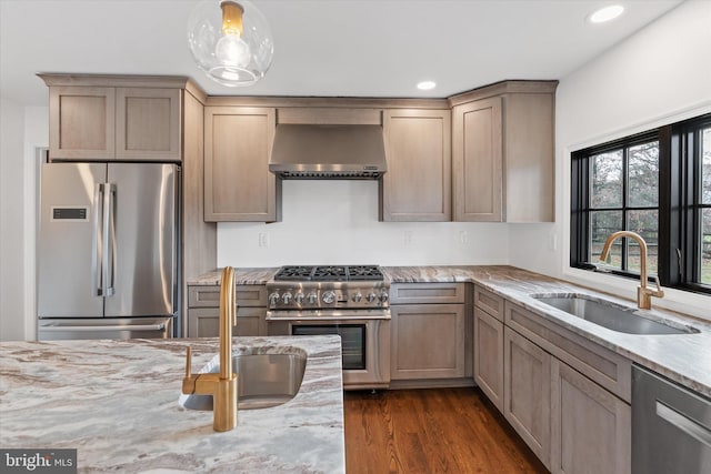 kitchen featuring wall chimney range hood, sink, hanging light fixtures, dark hardwood / wood-style floors, and premium appliances