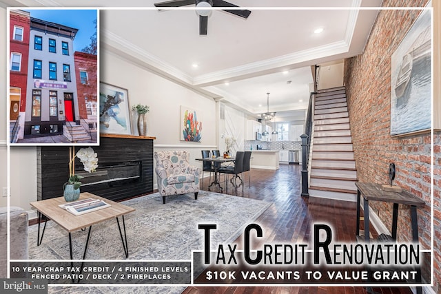 living room with a fireplace, dark hardwood / wood-style flooring, ceiling fan with notable chandelier, and ornamental molding