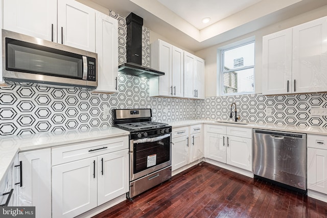 kitchen featuring dark hardwood / wood-style flooring, stainless steel appliances, wall chimney exhaust hood, and backsplash