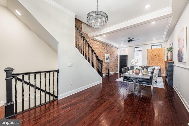 living room with crown molding, hardwood / wood-style floors, brick wall, and ceiling fan with notable chandelier