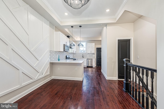 kitchen with white cabinetry, a raised ceiling, dark hardwood / wood-style floors, kitchen peninsula, and appliances with stainless steel finishes