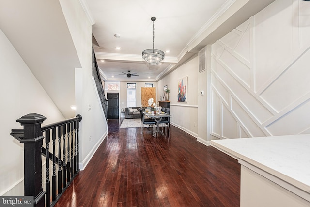 hallway with dark hardwood / wood-style floors, ornamental molding, and an inviting chandelier