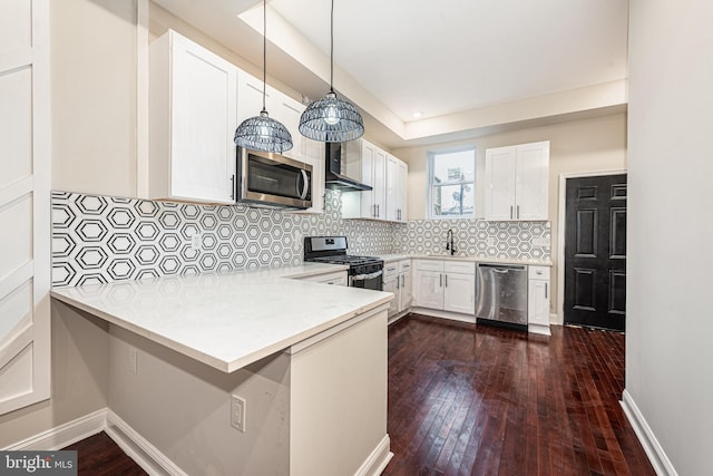 kitchen with decorative backsplash, appliances with stainless steel finishes, kitchen peninsula, dark wood-type flooring, and white cabinets