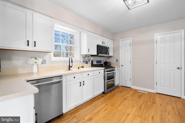 kitchen featuring white cabinetry, sink, light hardwood / wood-style flooring, and appliances with stainless steel finishes