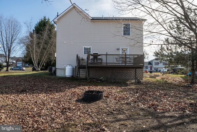 back of house featuring cooling unit, a deck, and a fire pit