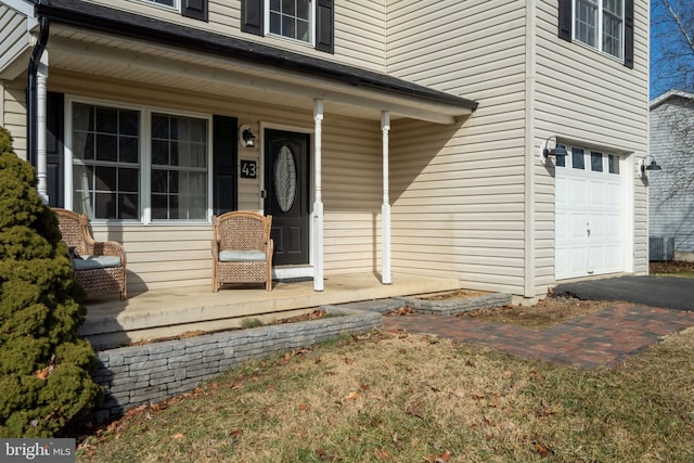 entrance to property featuring a porch, a garage, and central AC unit