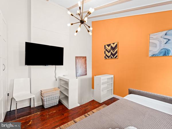 bedroom with a chandelier and dark wood-type flooring