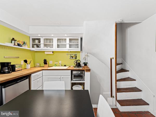 kitchen featuring white cabinets, stainless steel dishwasher, and sink