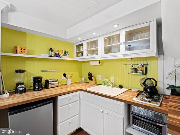 kitchen featuring butcher block counters, white cabinetry, sink, and stainless steel appliances