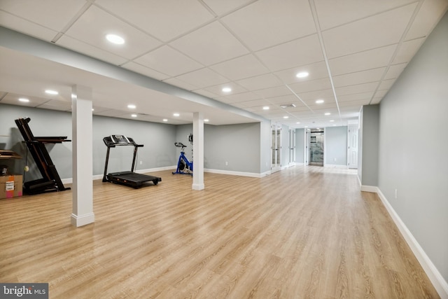 exercise room featuring a paneled ceiling and light hardwood / wood-style floors