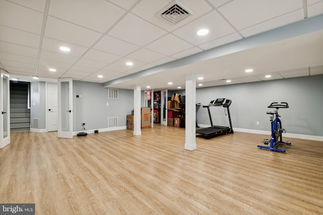 workout area featuring a drop ceiling and light hardwood / wood-style floors