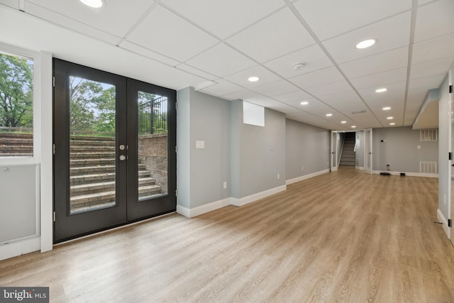 interior space with french doors, light hardwood / wood-style flooring, and a drop ceiling