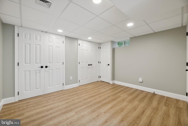 basement featuring a paneled ceiling and light wood-type flooring