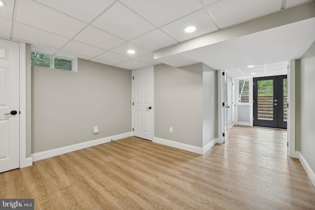 basement featuring a drop ceiling and light hardwood / wood-style flooring