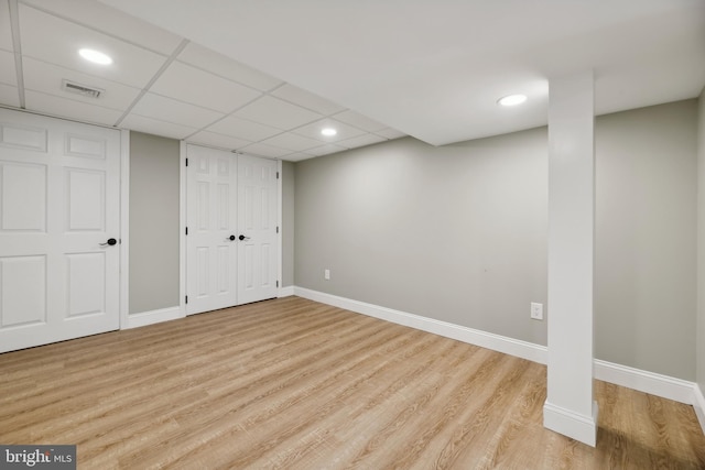 basement with a paneled ceiling and light hardwood / wood-style flooring