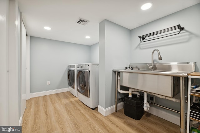 washroom with washing machine and dryer and light hardwood / wood-style flooring