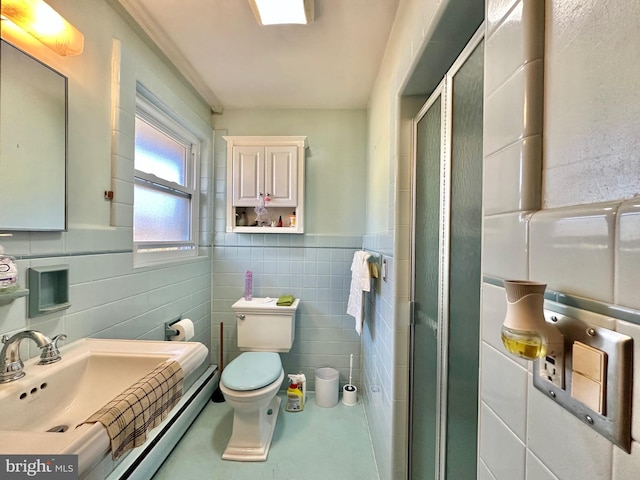 bathroom with toilet, sink, a shower with shower door, and tile walls