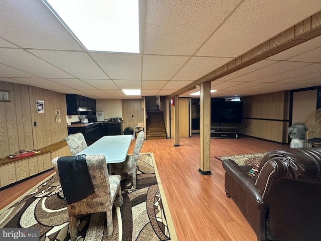 interior space featuring a paneled ceiling, light hardwood / wood-style floors, and wood walls