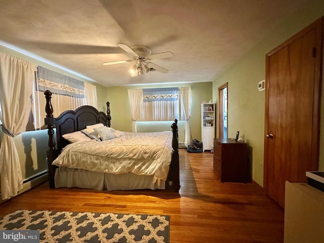 bedroom featuring hardwood / wood-style flooring, ceiling fan, and a baseboard radiator