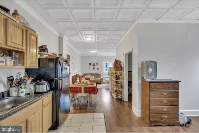 kitchen with light hardwood / wood-style floors, black fridge, crown molding, and sink