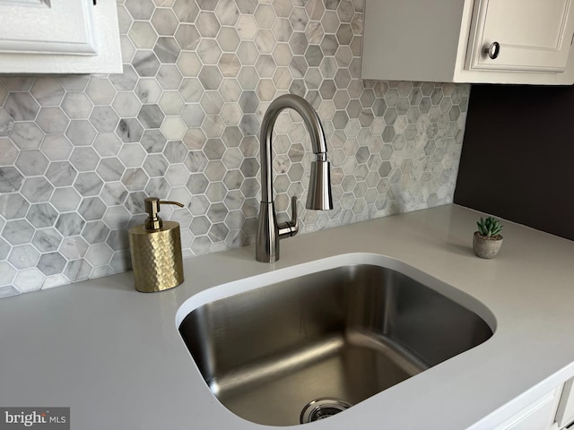 interior details with white cabinets, sink, and tasteful backsplash