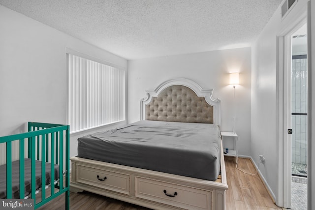 bedroom with light hardwood / wood-style flooring and a textured ceiling