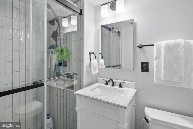 bathroom with vanity, toilet, and a shower with door