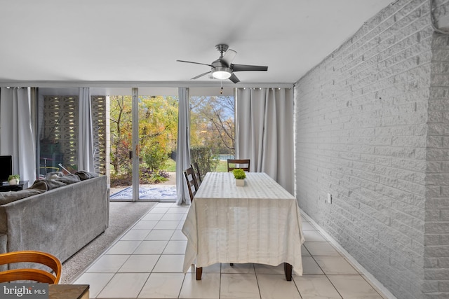 tiled dining area with ceiling fan, a healthy amount of sunlight, and brick wall