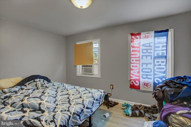 bedroom featuring multiple windows, hardwood / wood-style floors, and cooling unit