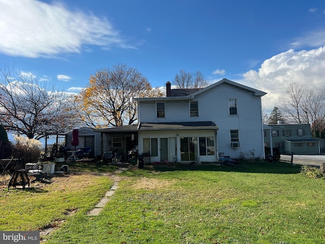 back of house featuring a lawn and a sunroom