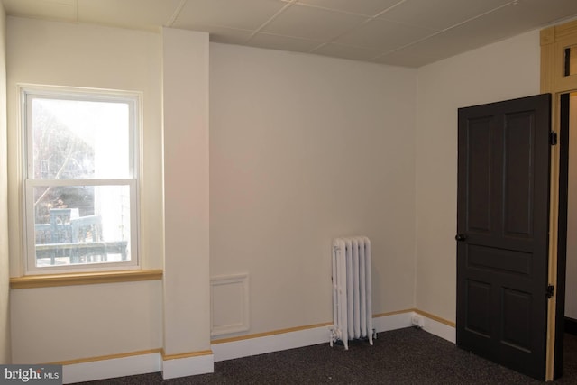 spare room featuring radiator and dark carpet