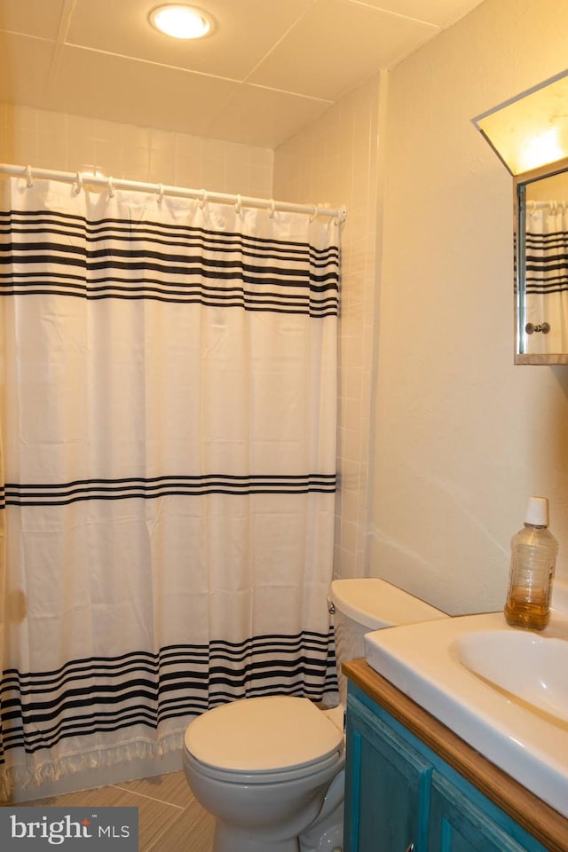 bathroom featuring tile patterned flooring, a shower with curtain, vanity, and toilet