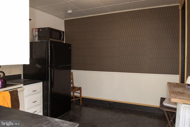 kitchen featuring white range with electric stovetop, black refrigerator, and white cabinets