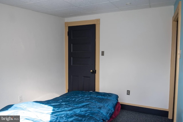 bedroom featuring dark colored carpet and a paneled ceiling