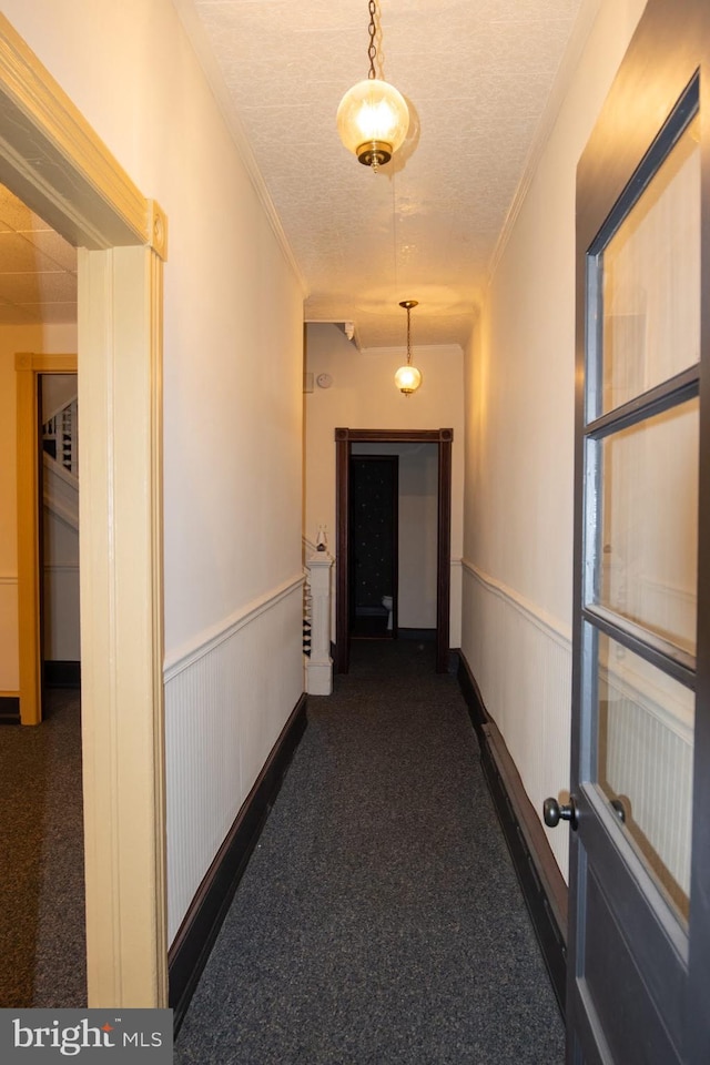 hall with a textured ceiling and ornamental molding