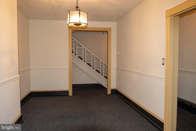 hallway with a drop ceiling and dark carpet