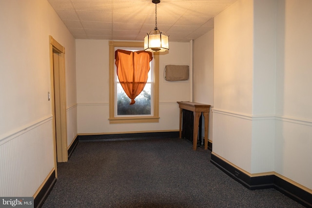 interior space featuring dark carpet and a drop ceiling