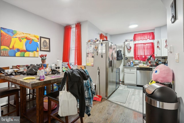 kitchen featuring stainless steel appliances, white cabinetry, and light hardwood / wood-style floors