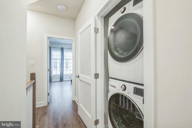 washroom with stacked washer / drying machine and dark wood-type flooring