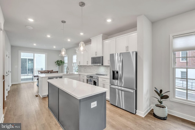 kitchen featuring kitchen peninsula, decorative light fixtures, sink, white cabinets, and stainless steel appliances