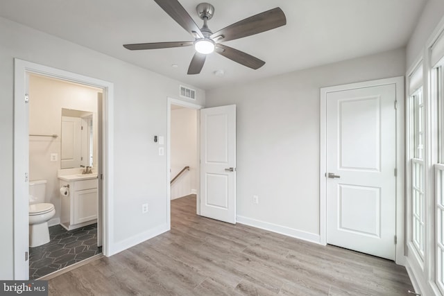 unfurnished bedroom with ceiling fan, a spacious closet, connected bathroom, light hardwood / wood-style floors, and a closet