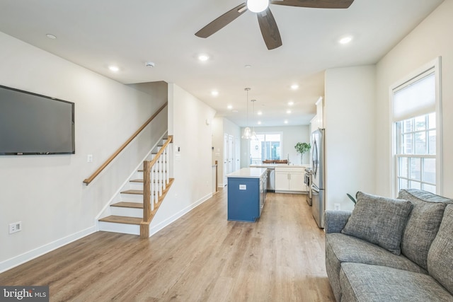 living room with sink, light wood-type flooring, and ceiling fan