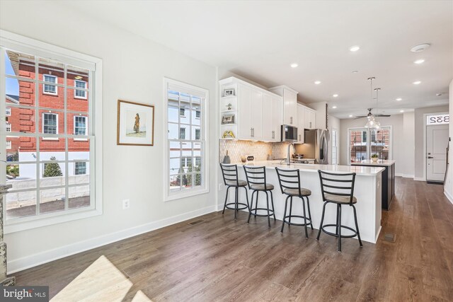 6832 General Davis NW, Washington, DC 20012 - kitchen with appliances with stainless steel finishes, white cabinets, light countertops, dark wood finished floors, and healthy amount of natural light