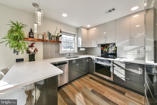 kitchen with sink, hanging light fixtures, decorative backsplash, dark hardwood / wood-style flooring, and stainless steel appliances