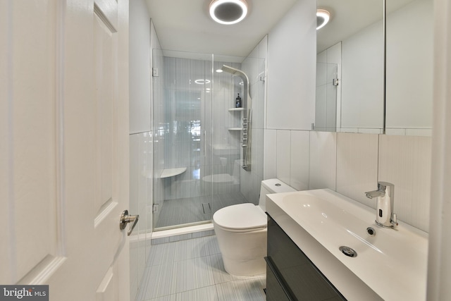 bathroom featuring vanity, a shower with door, tile patterned flooring, toilet, and tile walls