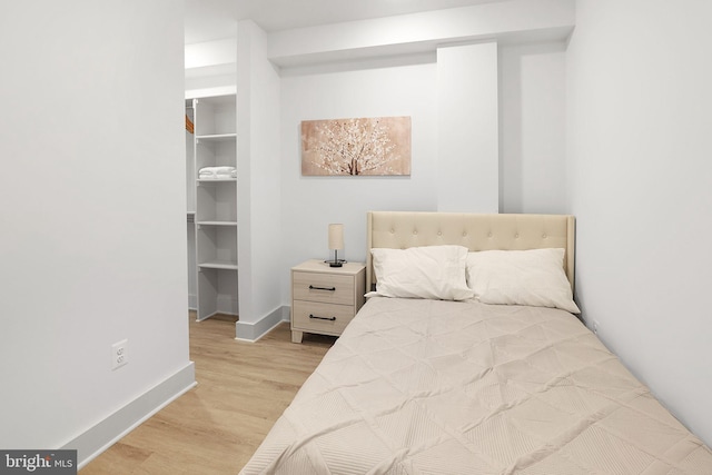 bedroom featuring a spacious closet, a closet, and light wood-type flooring