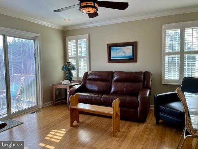 living room with a healthy amount of sunlight, light wood-type flooring, and crown molding