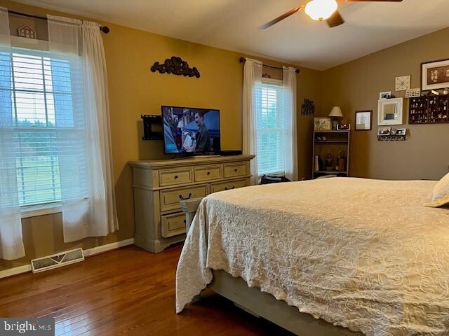 bedroom featuring multiple windows, ceiling fan, and dark hardwood / wood-style floors