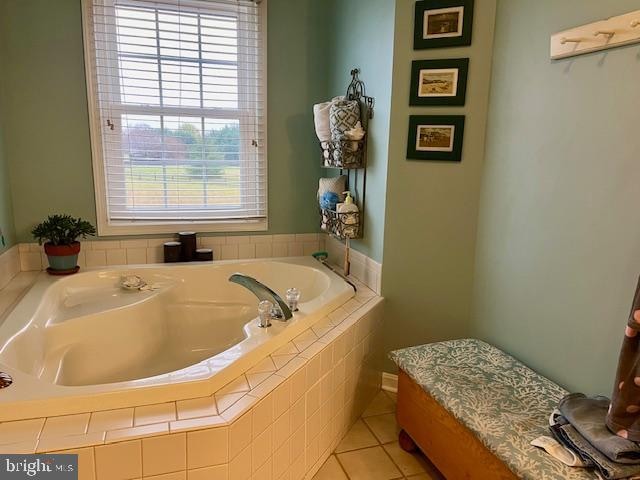 bathroom featuring tiled bath, tile patterned flooring, and a healthy amount of sunlight